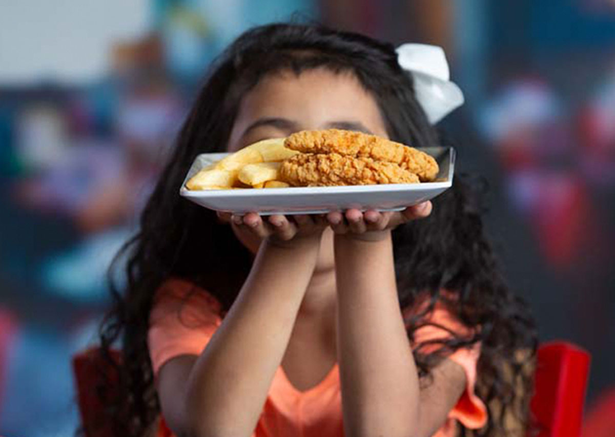Young Guest holding up her Cluck-a-doodles and Bottomless Steak Fries